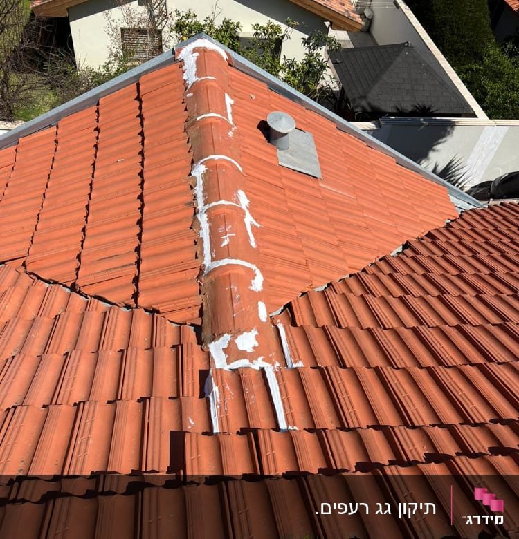 גג רעפים אדומים עם תיקוני איטום לבנים